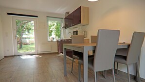 A modern kitchen with a dining area, featuring a table and chairs, a microwave, and cabinets.