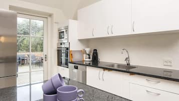 A modern kitchen with white cabinets, a stainless steel sink, and a coffee maker.