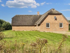 A brick house with a thatched roof, a small attached shed, and a well-maintained lawn. - 4 Star Holiday Home in Ulfborg (Ulfborg)