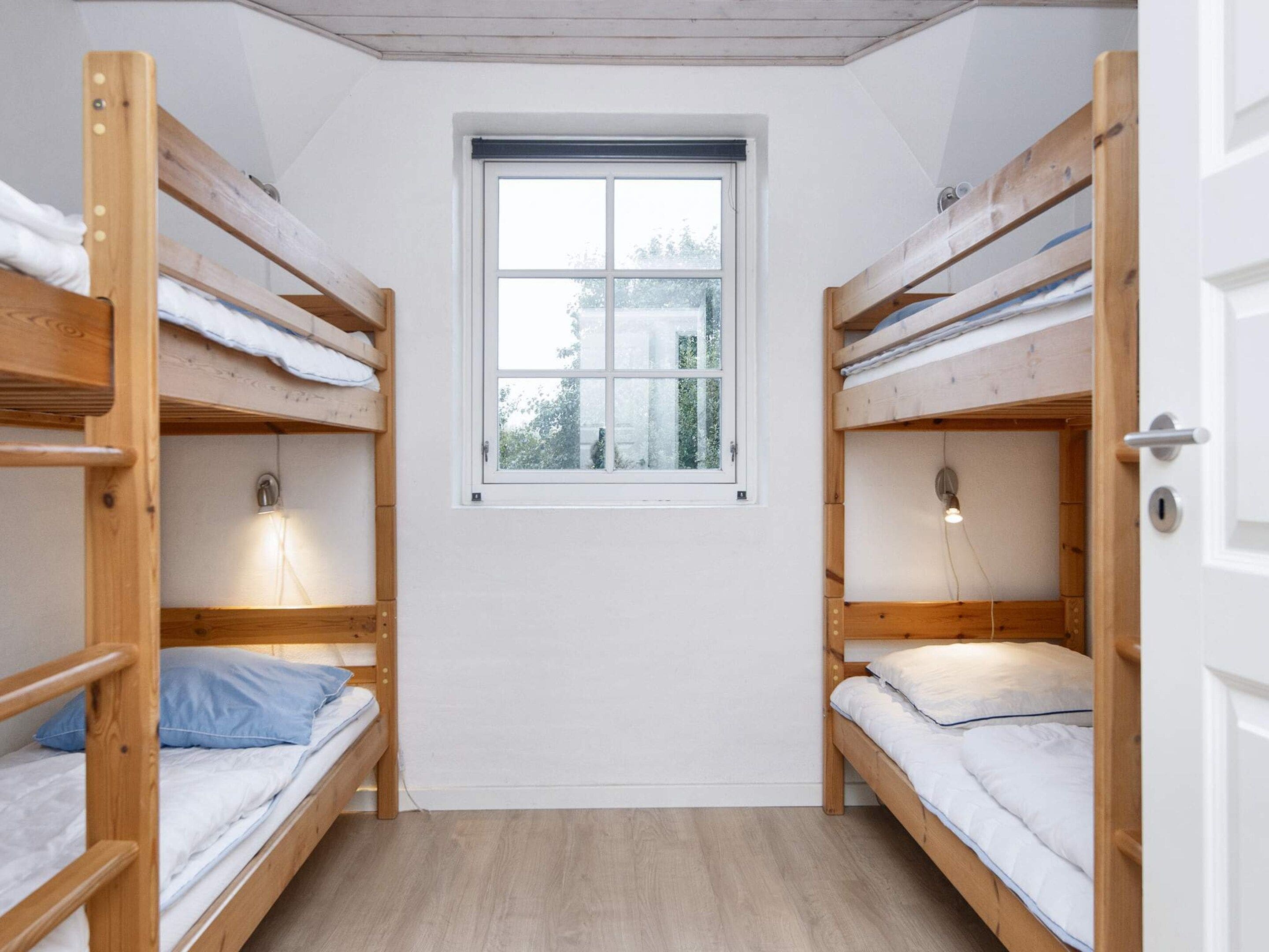 Ein Schlafsaalzimmer mit Etagenbetten, einem Fenster und einer Lampe.