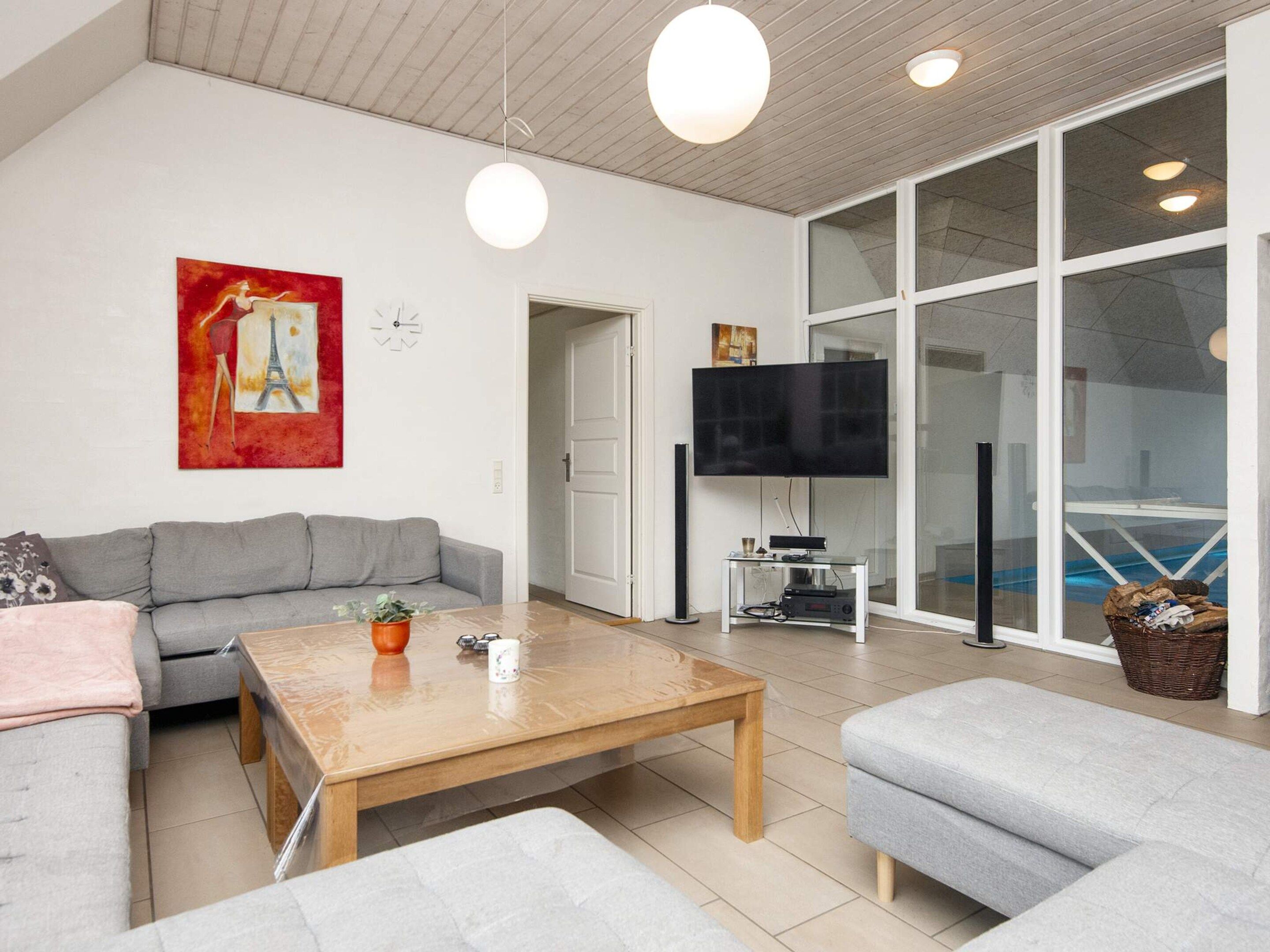 Un salon moderne avec un canapé gris, une table basse en bois et un téléviseur à écran plat fixé sur un meuble.