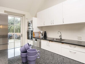 A modern kitchen with white cabinets, a stainless steel refrigerator, a microwave, and a coffee maker. - 4 Star Holiday Home in Ulfborg (Ulfborg)