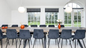 Un espace repas moderne avec une longue table, des chaises sombres et deux luminaires suspendus.