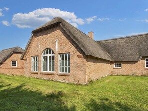 A brick building with a thatched roof, large windows, and a grassy lawn. - 4 Star Holiday Home in Ulfborg (Ulfborg)