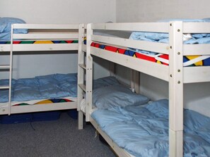 Une chambre avec un lit superposé, composé d’un lit du bas et d’un lit du haut, tous deux dotés de draps bleus.