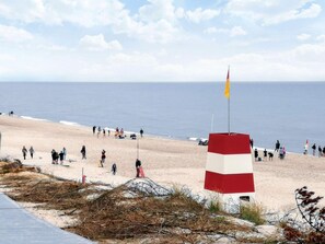 A beach with people, a flag, and a red and white structure. - 4 Star Holiday Home in Ringkobing (Ringkobing)