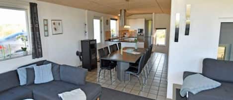 A modern living room with a sofa, a coffee table, and a dining area with chairs and a table.