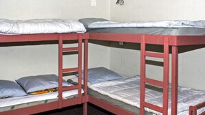 Une chambre avec un lit superposé comprenant trois lits, chacun étant équipé d’un matelas et d’oreillers.