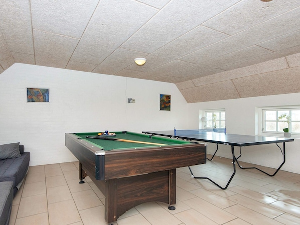 Une pièce équipée d’une table de billard, d’un canapé et d’une table de ping-pong.