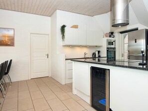 A modern kitchen with white cabinetry, a stainless steel range hood, and a built-in dishwasher.