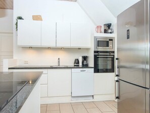 A modern kitchen with white cabinetry, a stainless steel refrigerator, a built-in oven, and a microwave. - 4 Star Holiday Home in Ulfborg (Ulfborg)