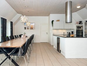 Une cuisine moderne dotée d’un îlot central, de meubles blancs et d’appareils électroménagers en acier inoxydable.