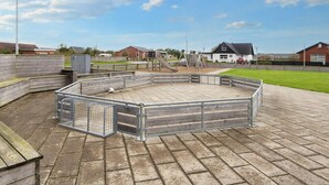 A playground with a fenced play area, a slide, and a swing set. - 4 Star Holiday Home in Harboore (Harboore)