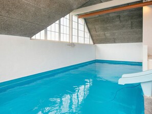Ein Innenpool mit schräg verlaufender Decke und Blick zum Himmel durch ein Fenster.