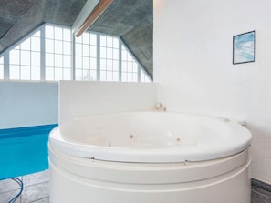 Ein großer, überdachter Pool mit einem Whirlpool im Vordergrund.