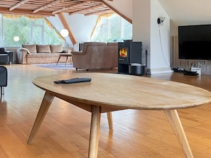 A spacious living room with a wooden table, a sofa, a television, and a wood-burning stove. - 4 Star Holiday Home in Karup J (Karup)