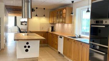 Una cocina moderna con armarios de madera, una isla central, electrodomésticos de acero inoxidable e iluminación colgante.