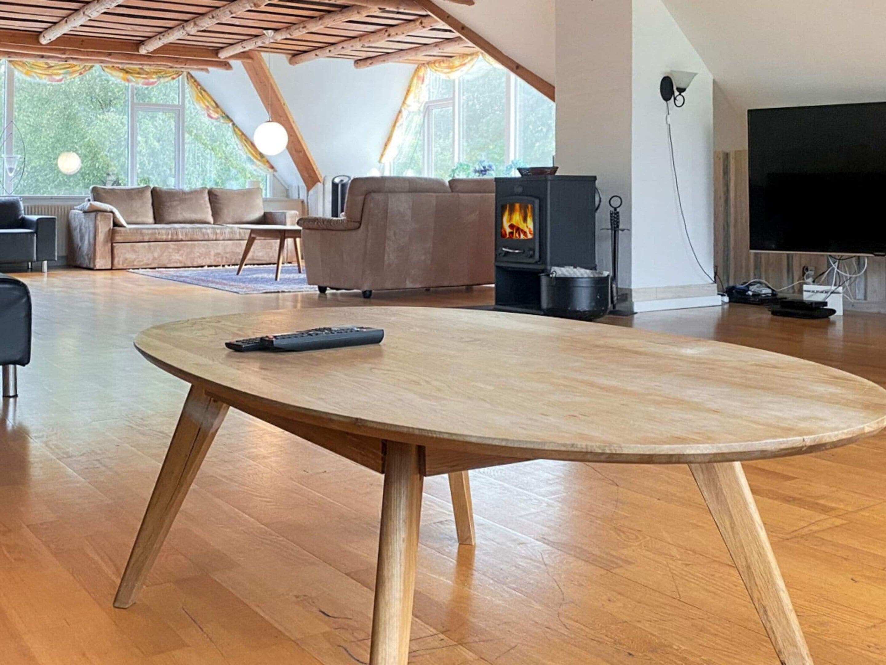 Una sala de estar moderna con una mesa de madera, un sofá, un televisor y un estufa de leña.