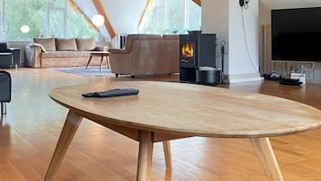 Una sala de estar moderna con una mesa de madera, un sofá, un televisor y un estufa de leña.