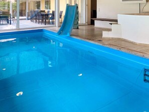 A swimming pool with a slide, a sun lounger, and a view of an outdoor dining area. - 4 Star Holiday Home in Karup J (Karup)