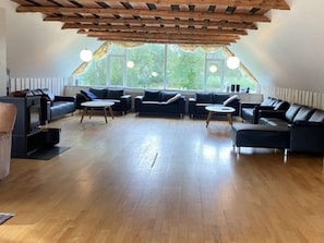 A spacious living room with a sloped ceiling, large windows, and a fireplace. - 4 Star Holiday Home in Karup J (Karup)