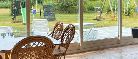 A dining area with a table and chairs, large windows, and a view of a playground.