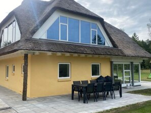 A house with a thatched roof, yellow exterior walls, and a patio with outdoor seating. - 4 Star Holiday Home in Karup J (Karup)