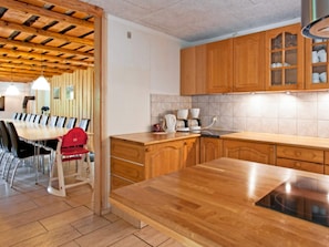 A modern kitchen with wooden cabinets, a dining table with chairs, and a built-in stove. - 4 Star Holiday Home in Karup J (Karup)
