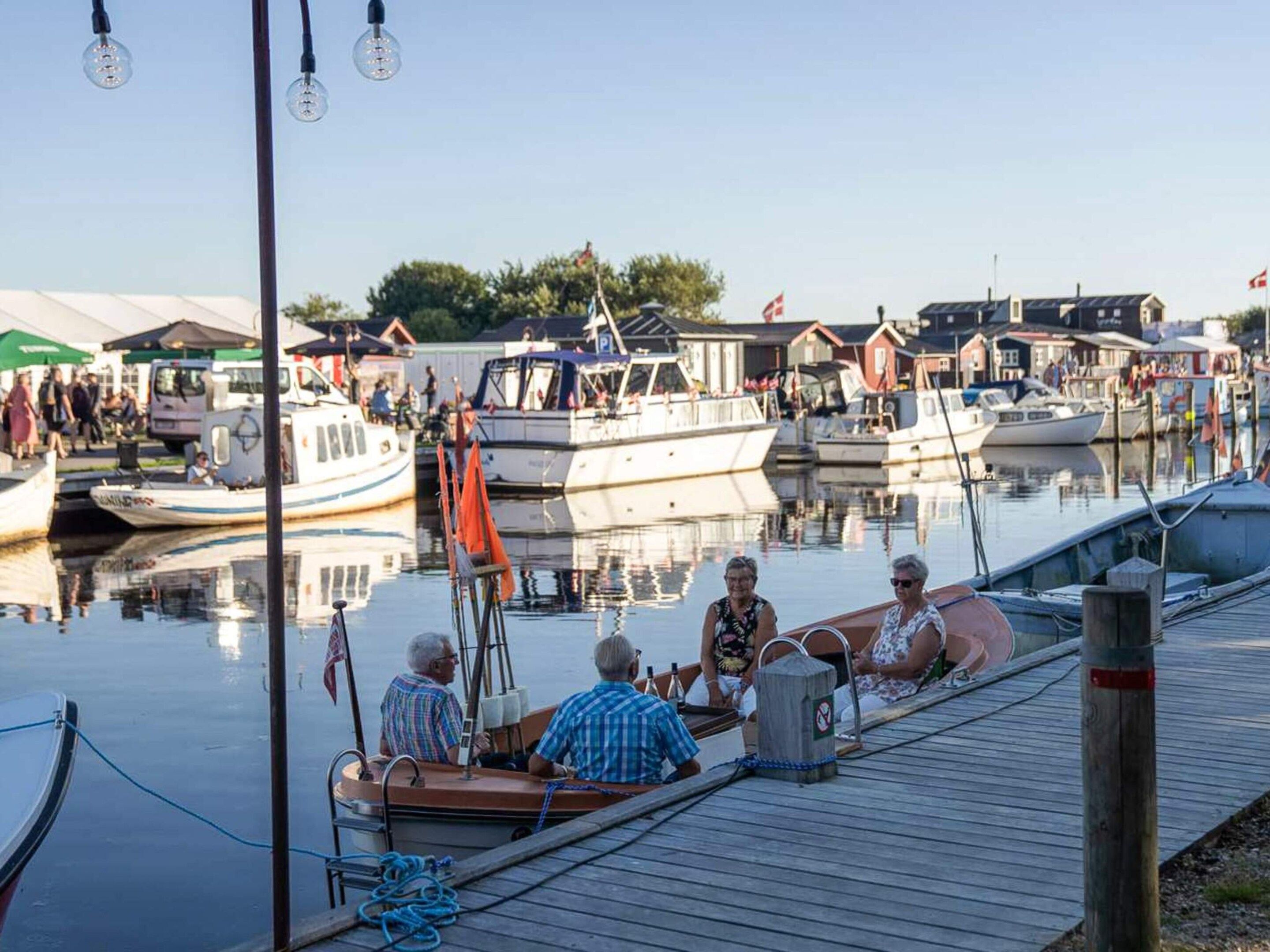 A marina with boats docked, a wooden dock, and a clear sky.