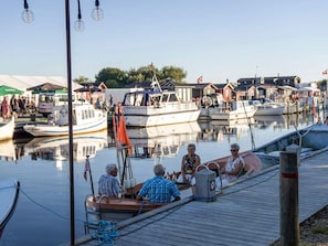 En småbåtshamn med förtöjda båtar, en träbrygga och en klar himmel.