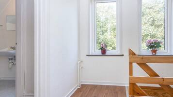 A room with two windows, a wooden bench, and a potted plant on the windowsill.