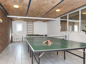 A ping pong table with a net in a room with a brick wall and a window. - 18 Person Holiday Home in Skjern (Skjern)