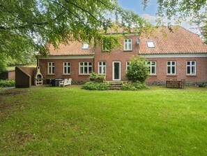 A brick house with a tiled roof, a brick oven, and a well-maintained lawn.