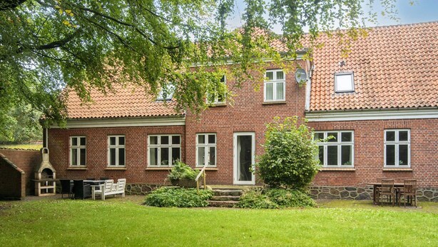 A brick house with a tiled roof, a front door, and a small garden with a bench and a table. - 18 Person Holiday Home in Skjern (Skjern)