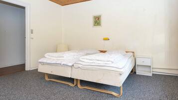 A bedroom with a bed, a bedside table, a lamp, and a small cabinet.