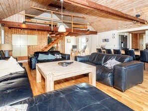 A spacious living area with leather sofas, a wooden coffee table, and a staircase.