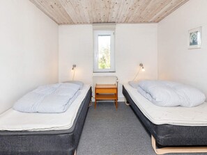 Une chambre avec deux lits, une fenêtre, un radiateur et une petite table.
