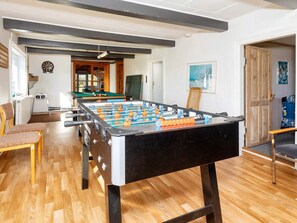 A room with a foosball table, wooden flooring, and a door leading to another room. - 4 Star Holiday Home in Thyholm (Thyholm)