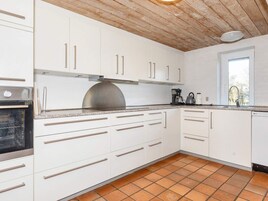 Una cocina con gabinetes blancos, una campana extractora de acero inoxidable, una cafetera y un lavavajillas.