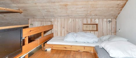 Una habitación pequeña con paneles de madera, una cama, un televisor y un enchufe.