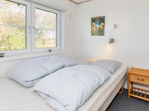 A bedroom with a bed, a window, a wall-mounted light, and a poster. - 4 Star Holiday Home in Thyholm (Thyholm)