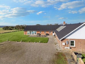 A two-story building with a gravel driveway, a grassy lawn, and a clear sky.