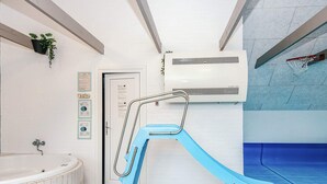 A swimming pool area with a blue pool ladder, a white bathtub, and an air conditioning unit on the wall. - Luxury Pool House by Sea - By Traum Ferienwohnungen (Ulfborg)