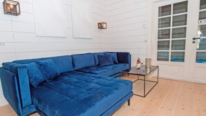 A blue sectional sofa in a room with white paneled walls and a wooden floor. - 4 Star Holiday Home in Spottrup (Spøttrup)