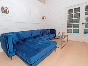 Un sofá azul modular en una habitación con paredes blancas de paneles y suelo de madera.