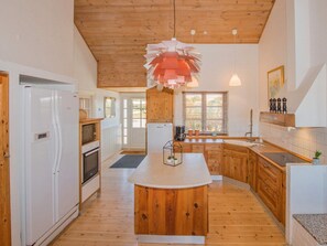 Una cocina con armarios de madera, una isla central y una lámpara colgante.
