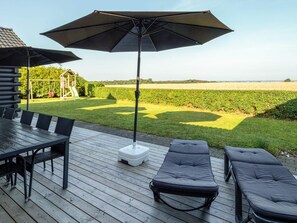 A deck with a table and chairs, a lounge area with cushions, and a large umbrella. - 4 Star Holiday Home in Spottrup (Spøttrup)