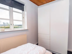 A bedroom with a bed, a window with a view, a radiator, and a wardrobe.