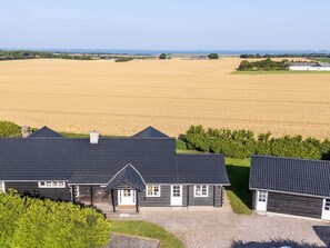 A large, modern house with a dark roof and white trim, surrounded by a vast field and a clear sky. - 4 Star Holiday Home in Spottrup (Spøttrup)