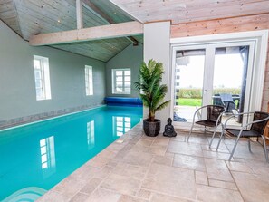 An indoor swimming pool with clear water, a potted plant, and a Buddha statue. - 4 Star Holiday Home in Spottrup (Spøttrup)
